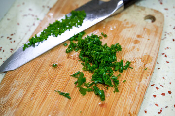 A dollop of chopped chives chopped with a knife on a cutting board