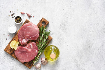 Fresh pork steaks on a light concrete background, raw meat with spices on the kitchen table, top view - obrazy, fototapety, plakaty