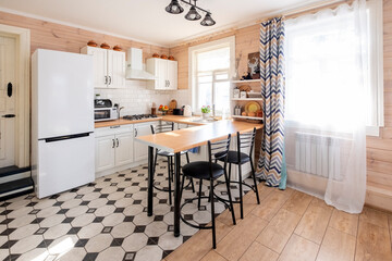 Modern white u-shaped kitchen in scandinavian style. In a bright rustic house where kitchen is combined with the living room