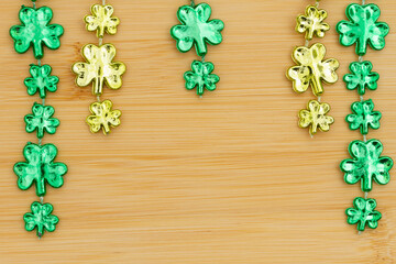 Green shamrocks on light brown grained wood background