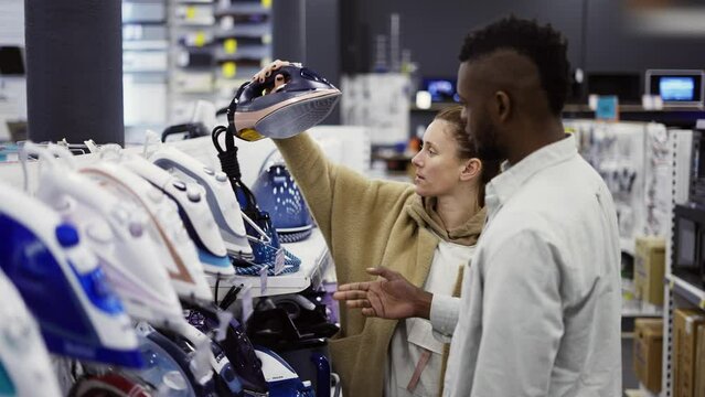 Shop assistant helps the woman to choose an iron