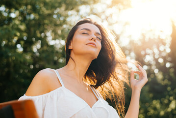 Portrait of young mixed race woman with closed eyes enjoying outdoor recreation. Pretty brunette...
