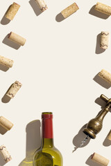 Frame from wine corks, vintage corkscrew and red wine bottle on beige background with shadows at...
