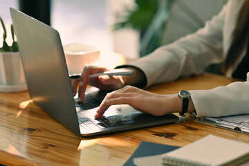 Close up woman&rsquo;s hand using a laptop in the office. Holding a pen and typing, for business, finance and technology concept.
