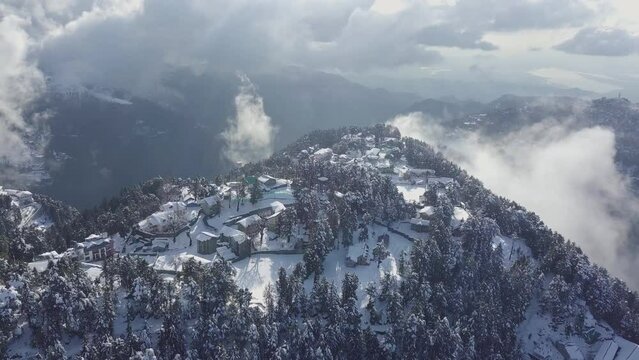 Video of fresh snow fall on the mountains and trees with a house in the distance with misty clouds enveloping the hills, Dalhousie, Himachal Pradesh.