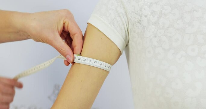 girth of the female arm of the forearm with a centimeter tape professional tailoring, fitting, parameters, a seamstress in the atelier with a client, applies a centimeter tape, takes the size