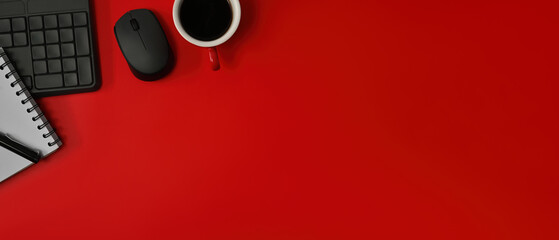 Top view flat lays of note book, keyboard and a cup of coffee on a red background with a lot of...