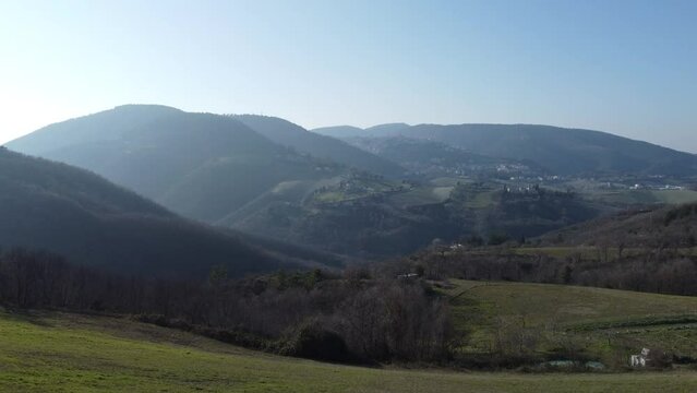 Hills, forrest, meadow, fields at sunset in Italy, Marken, Umbria. Italian town Arcevia in the background.