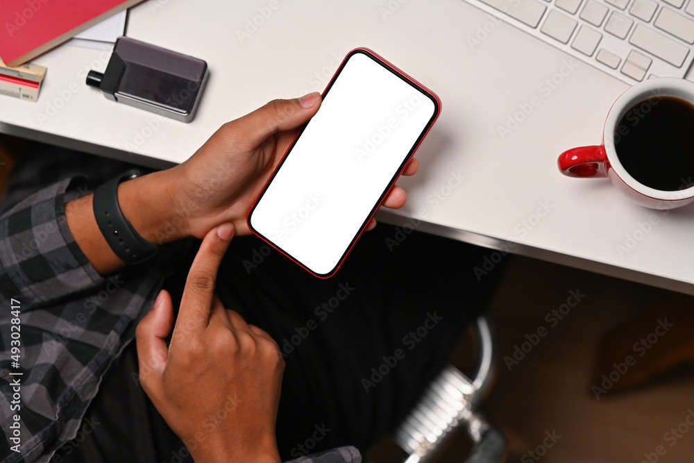 Poster top view with creative male hand using empty screen of smartphone while sitting at workspace.