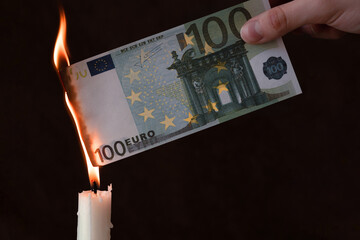 inflation in the eurozone concept, hand holds a banknote of 100 euros on fire, depreciation of money