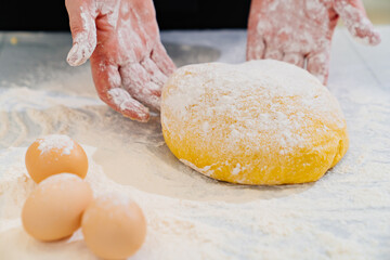 women's hands with dough, flour and eggs on table
