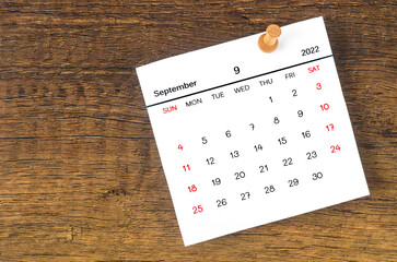 September 2022 calencar and wooden push pin on wooden background.