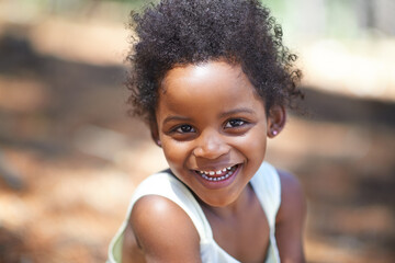 She loves playing in the woods. Portrait of an adorable little girl smiling at the camera while enjoying a day outdoors. - obrazy, fototapety, plakaty