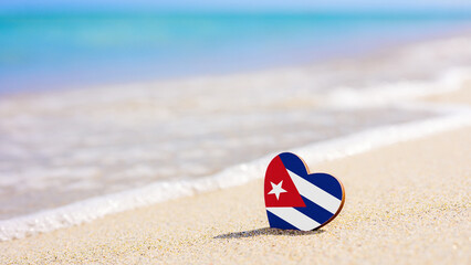 Flag of the Cuba in the shape of a heart on a sandy beach. The concept of the best vacation in Cuba