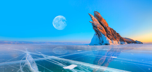 Ogoy island on winter Baikal lake with transparent cracked blue ice with full moon at sunrise - Baikal, Siberia, Russia 