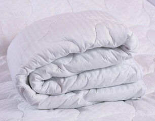 Large soft blanket made of cotton fabric and filler "synthetic fluff" or padding polyester. A neatly folded accessory for the bed. Photos about the production and sale of home textiles