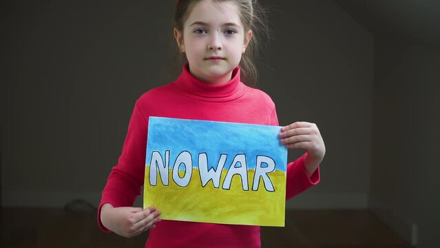 Portrait serious girl protesting armored conflict holding banner with inscription No War at blue yellow flag of Ukraine. Crisis, peace, stop aggression in whole world