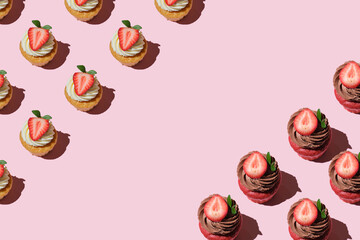 Pattern made of home cookies with strawberries and cream on a pink background. copy space for text, cupcake with big strawberry on top. Flat lay style.