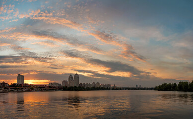 Embankment on Obolon in Kyiv. Summer landscape with reflection of the colorful evening sky in the Dnipro