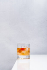 Vaso de vermut rojo con hielo decorado con cerezas y rodajas de naranja sobre mesa blanca	