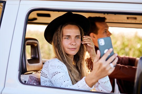 Happy adult beautiful young woman inside an old vintage trendy yellow van enjoying the trip and travel lifestyle looking at mobile phone with internet connection. people lifestyle, alternative people - Powered by Adobe