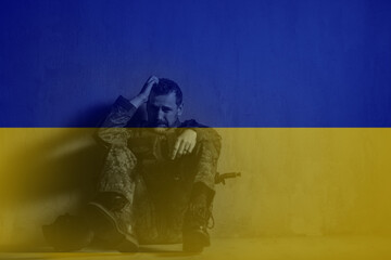 Double exposure of frustrated military soldier sitting crying alone in boot camp and Ukrainian flag.