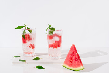 Dos vasos de zumo de sandía con trozos de sandia y hielo sobre fondo claro	