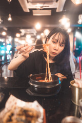 Portrait happy smile young adult asian woman eating noodle at Korean meal.