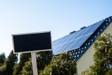 Blank Black billboard against new ecologic house with solar panels Empty mockup template Blackboard...