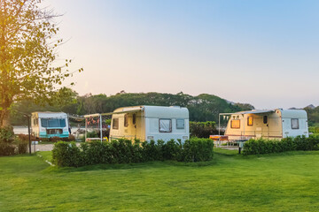 Cozy retro travel trailer Caravan on green grass before sunset near riverside in peaceful...
