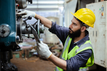 Man engineer wear yellow helmet holding tablet and uniform working at industrial workshop. handsome workman with beard on face ​in factory. Copy space.