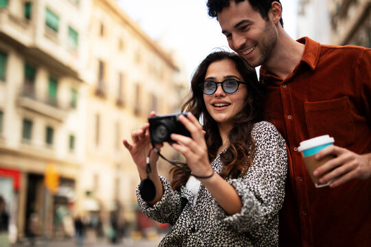 Traveling couple taking photos with camera. Loving couple walking through the city