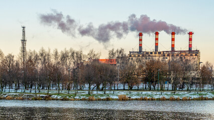 Obraz premium Power station with reservoir in winter. Beautiful seaside winter sunset with a smoking factory chimney.