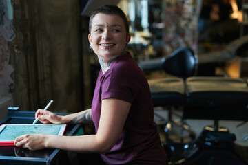 Caucasian tattoo artist  designing motifs on digital tablet