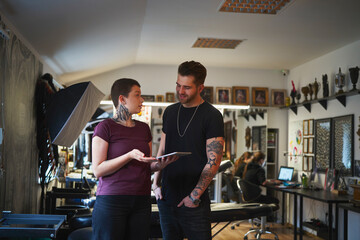 Adult woman and man talking together in tattoo studio