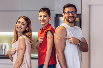 Coronavirus Vaccination. Vaccinated Family Of Three With Adhesive Bandage On Arms Posing At Home...
