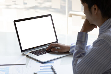 Thinking man working on laptop with blank screen for copy space on office desk.