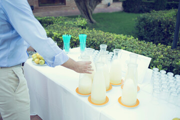 Mesa de limonada fresca en un catering con personas sirviéndose refrescos de limón en vasos