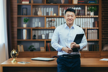 Portrait of a successful financier, Asian in a shirt looks at the camera and smiles in a classic...
