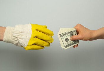 The builder's hand in a protective glove takes money from the customer.	 - 493052639