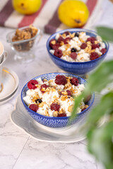 Blue bowl of cottage cheese with berries, honey and nuts for breakfast, selective focus.