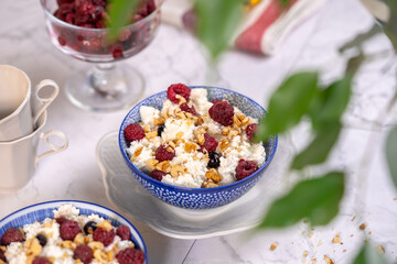 Blue bowl of cottage cheese with berries, honey and nuts for breakfast, selective focus.