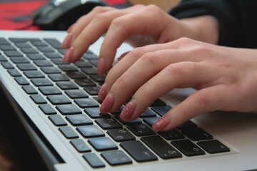 Woman typing on laptop keyboard, hands on keyboard close up, floating focus