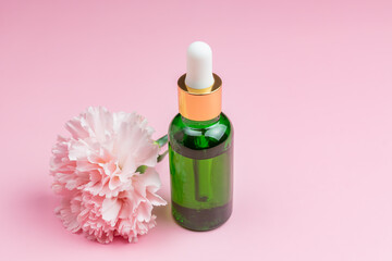Green glass Serum bottle on pink background. Trendy beauty product for young skin. Additional...