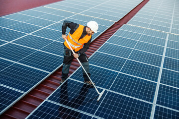A focused worker cleaning solar panels form dust.