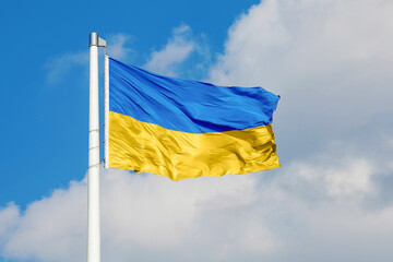 Ukrainian national flag waving on the wind against blue cloudy sky