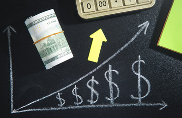Dollar growth chart on blackboard with arrow and money.