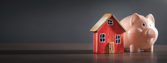 Piggy bank and house model on the table.