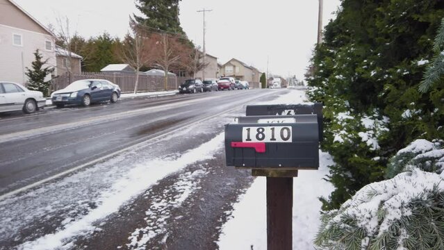 Mailboxes by side of road on snowy day as cars drive past, Slide Left