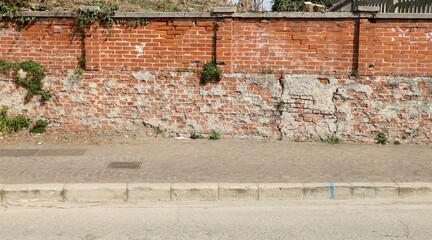 Grunge boundary brick wall, porphyry sidewalk and asphalt road in front. Background for copy space